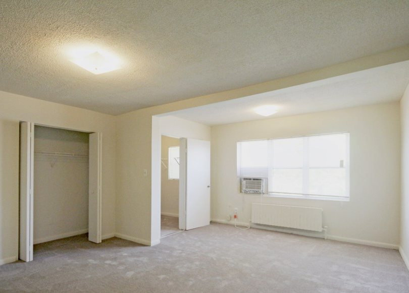 an empty living room with a window and a door